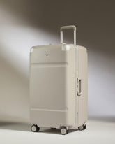 Beige suitcase with a visible brand logo on a gradient background