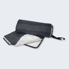 Black and white quilted blanket with strap on a light gray background