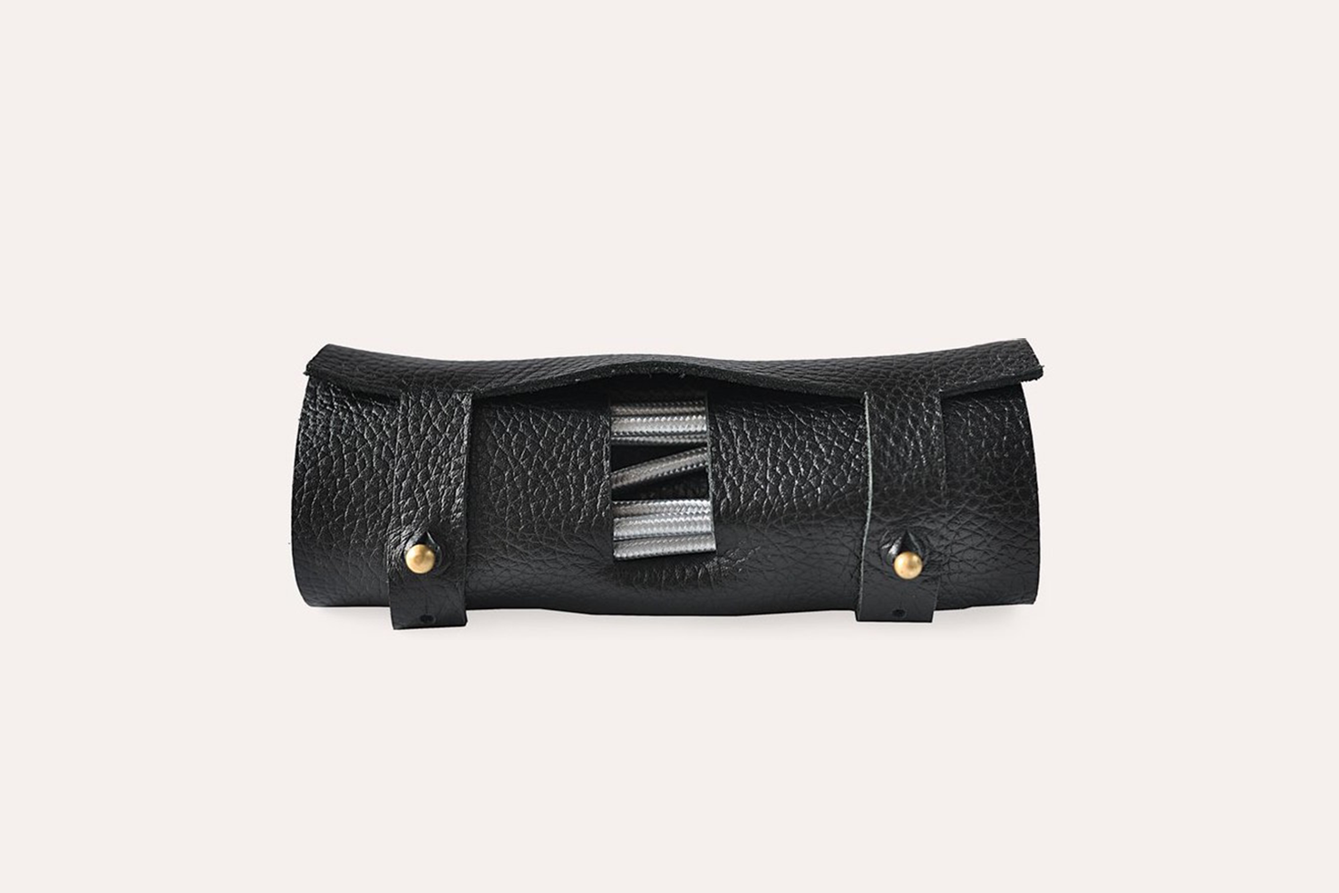 Black leather tool roll with metallic accents on a light beige background
