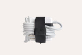 White earbud with black clip on a light gray background