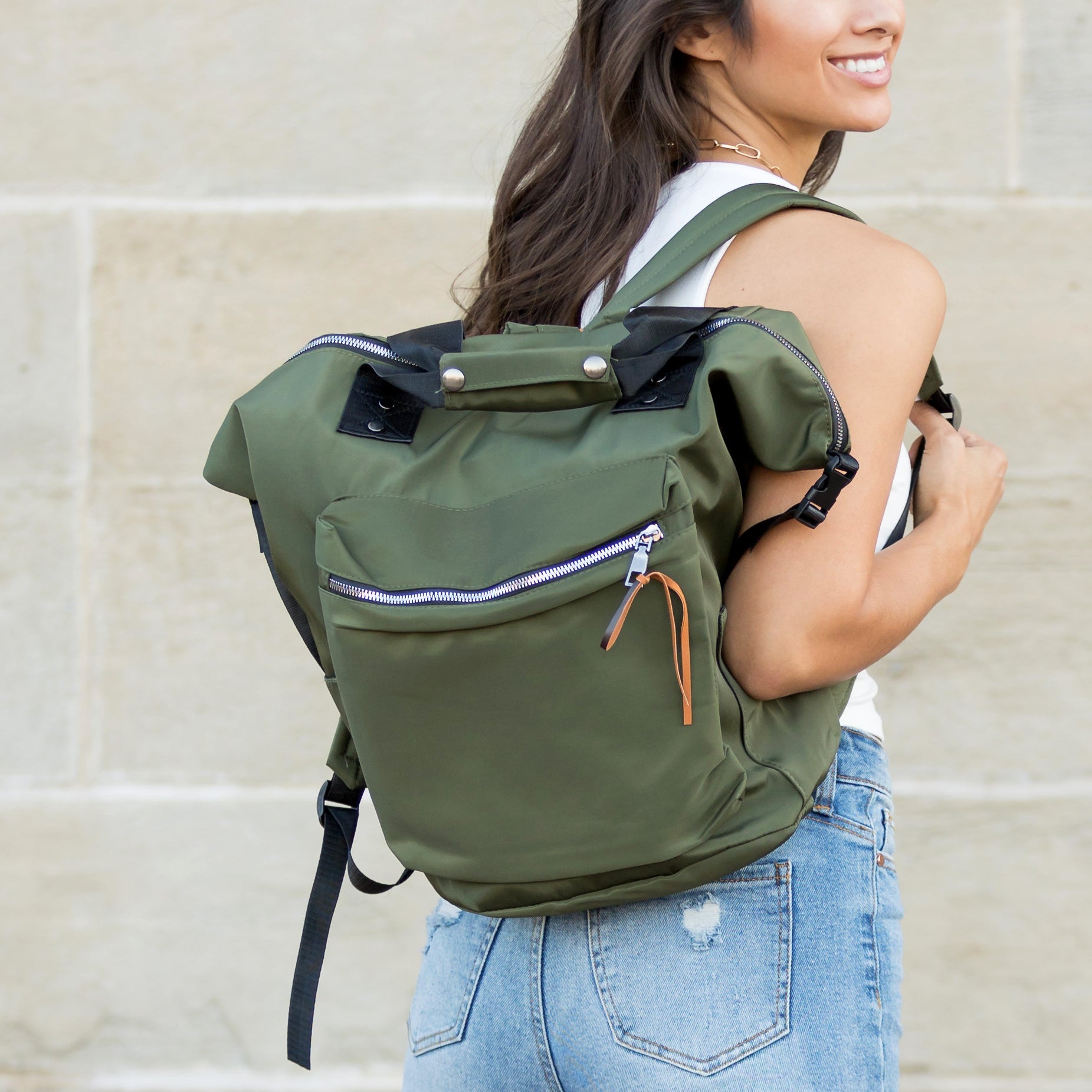 Person wearing a green backpack against a beige wall