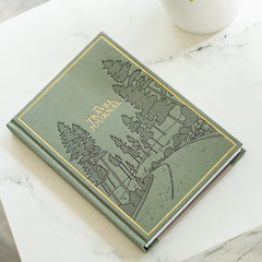 Green travel journal with embossed design on a marble surface