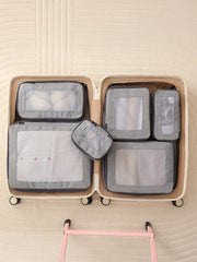 Open suitcase with gray packing cubes inside on a beige textured background