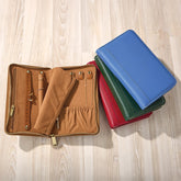 Set of leather-bound notebooks in various colors on a wooden surface