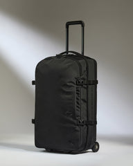Black suitcase with wheels on a light gray background