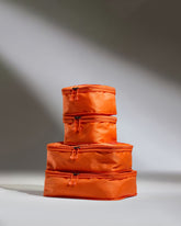 Stack of orange packing cubes on a gray background