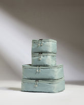 Set of three light blue packing cubes stacked on a white background