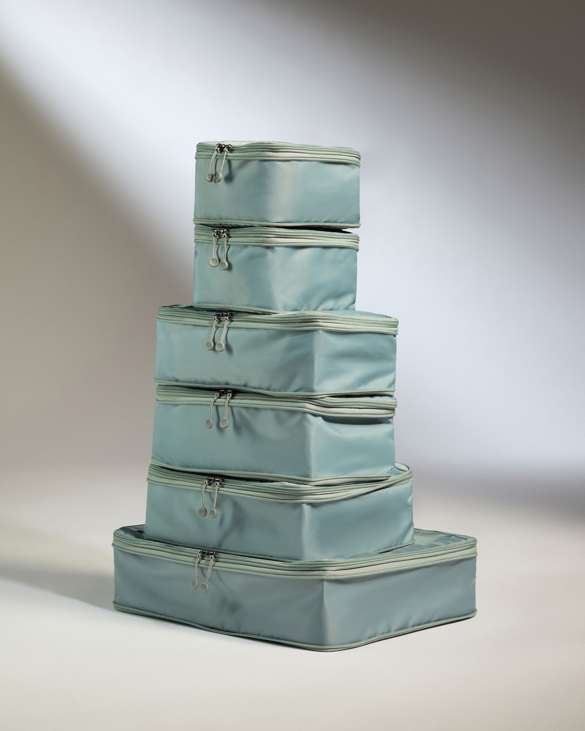 Set of four light blue packing cubes stacked on a neutral background