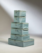 Set of four light blue packing cubes stacked on a neutral background