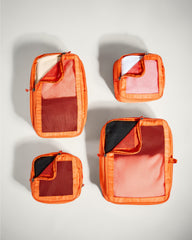 Set of orange travel packing cubes on a light gray background