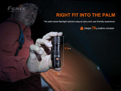 Person holding a palm-sized flashlight with product details on a dark background