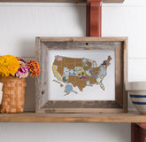 Framed map of the United States with floral designs on a wooden shelf.