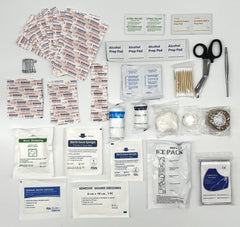 First aid kit contents including bandages, alcohol prep pads, scissors, and other medical supplies on a white background.