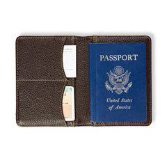 Brown leather passport holder with a blue U.S. passport inside on a white background