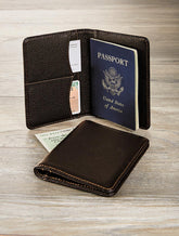 Brown leather wallet and passport holder with a U.S. passport on a wooden surface