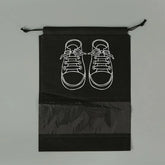 Black drawstring bag with white line drawing of sneakers on a gray background