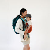 Woman holding a child wearing a backpack on a white background
