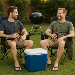Two men sitting in lawn chairs with beer bottles, a cooler, and a grill in the background.