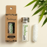 Bamboo switch white floss with packaging and a few leaves on a light background