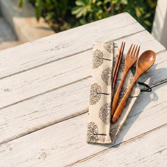 Wooden cutlery set on a patterned napkin on a wooden table outdoors
