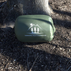 Green hammock bag with 'Hanging High Hammocks' logo on a forest floor background
