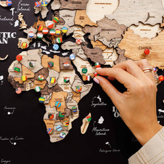 Wooden world map with country flags and a hand interacting with it