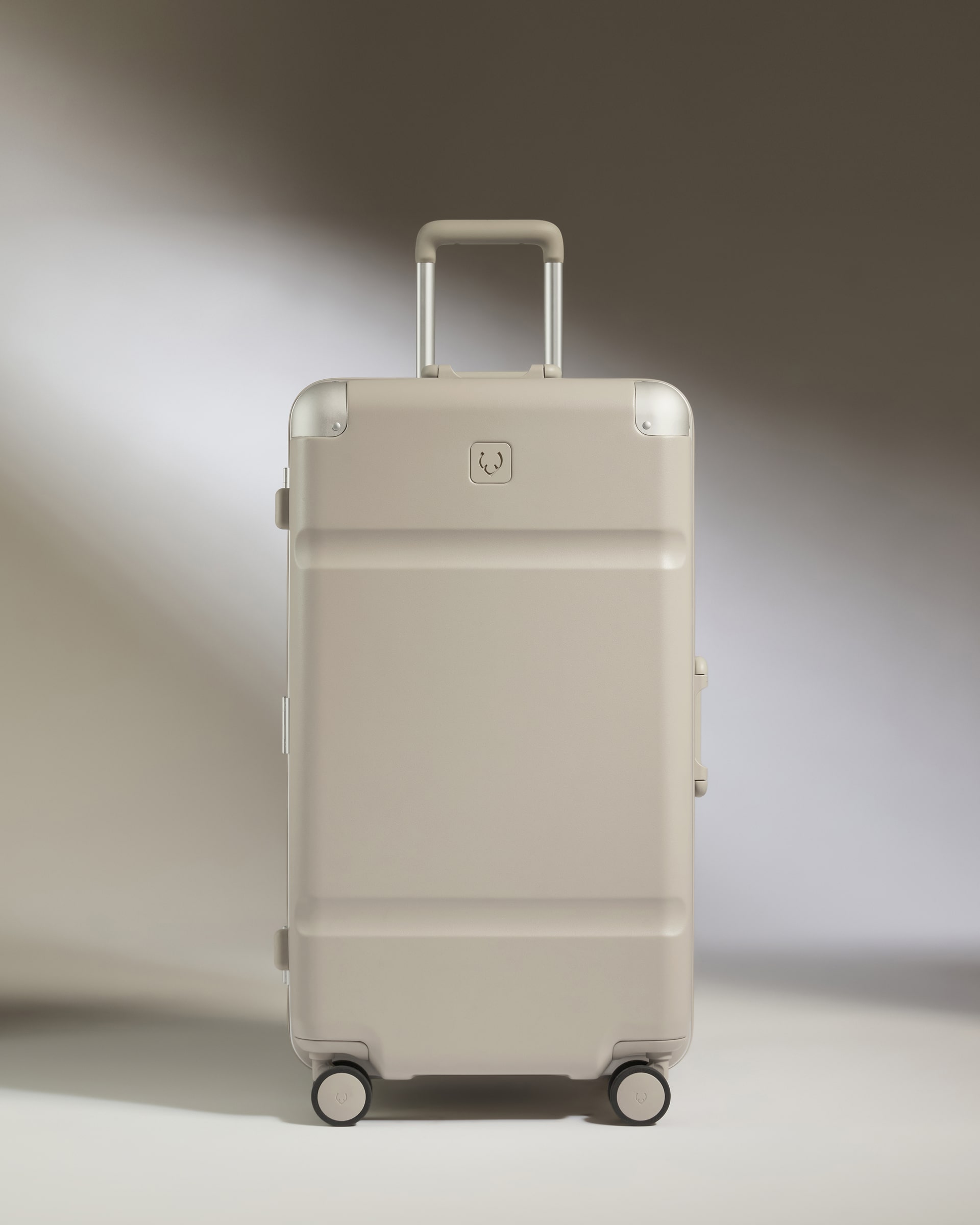 Beige suitcase with a brand logo on a gradient background