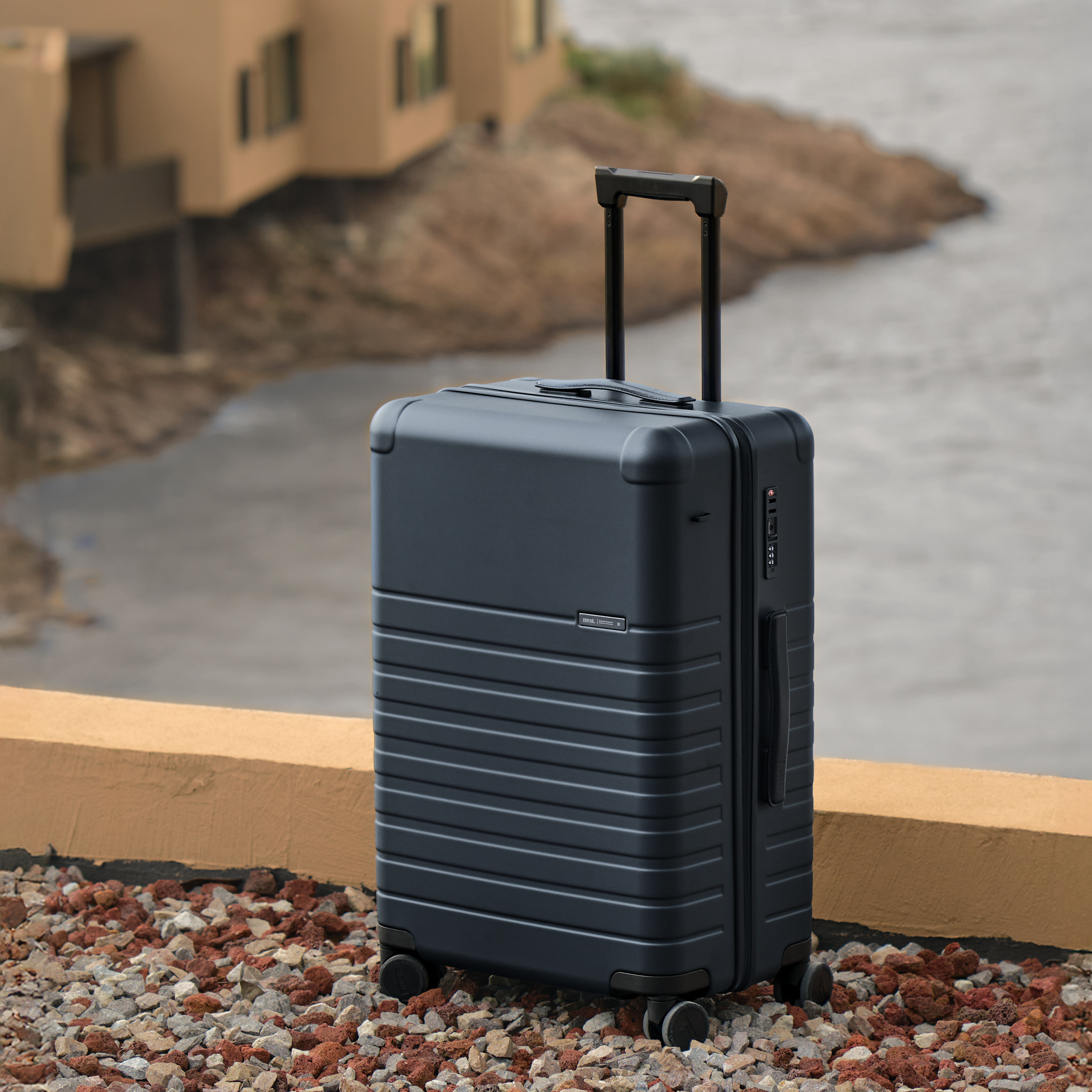 Black suitcase on wheels near a building with a blurred background