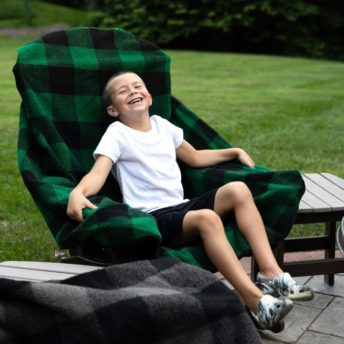 Child sitting on a green and black checkered chair outdoors