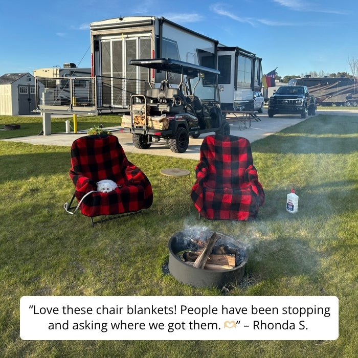 Two red and black plaid chairs by a campfire with RVs in the background.