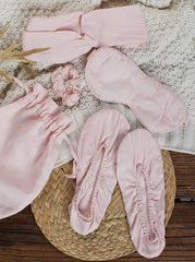 Set of pink baby accessories including socks, headbands, and a scrunchie on a textured surface.