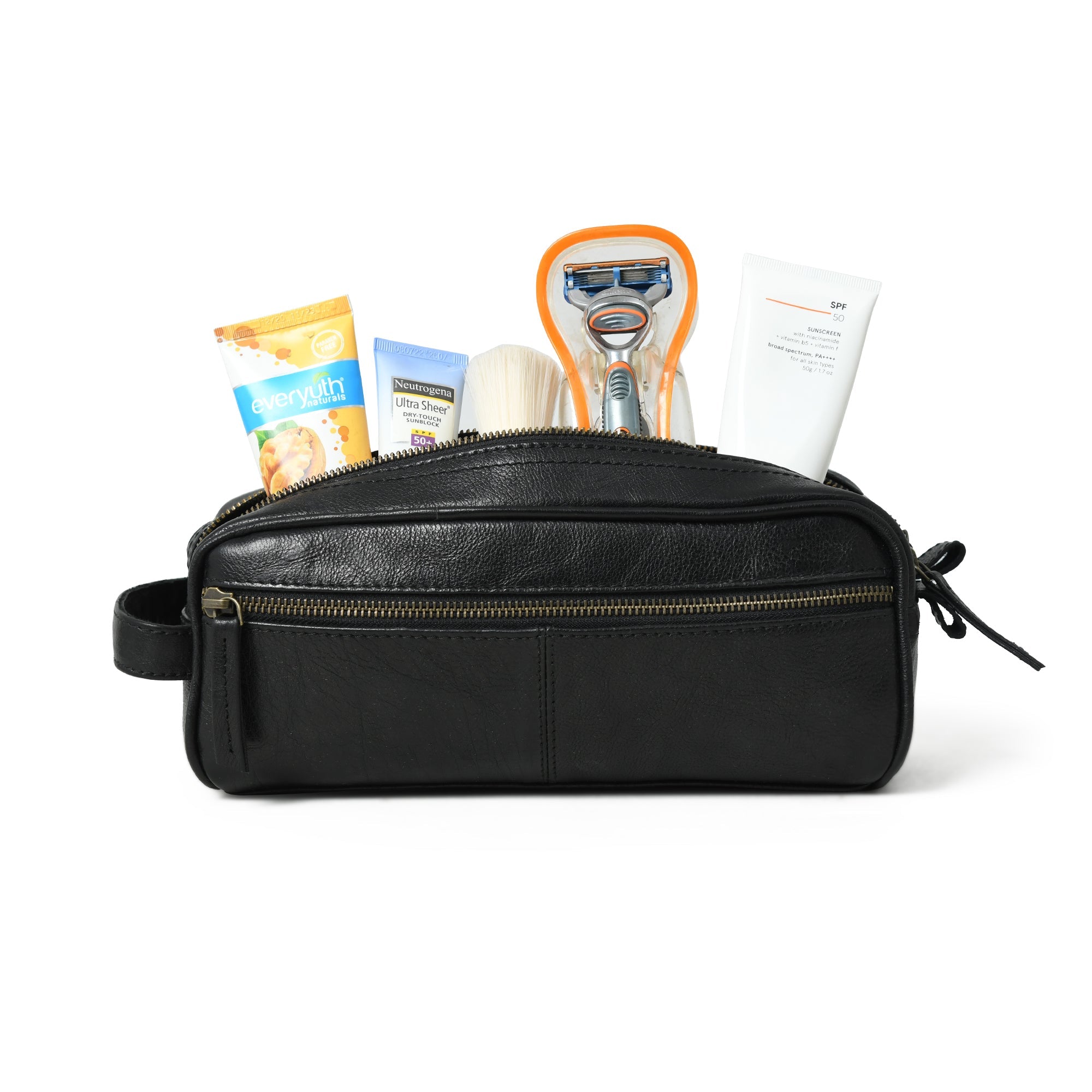 Black leather toiletry bag with various travel items on a white background