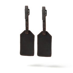 Two black leather luggage tags with brown straps on a white background
