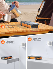 Portable power bank on a table with solar and USB inputs, beach setting.