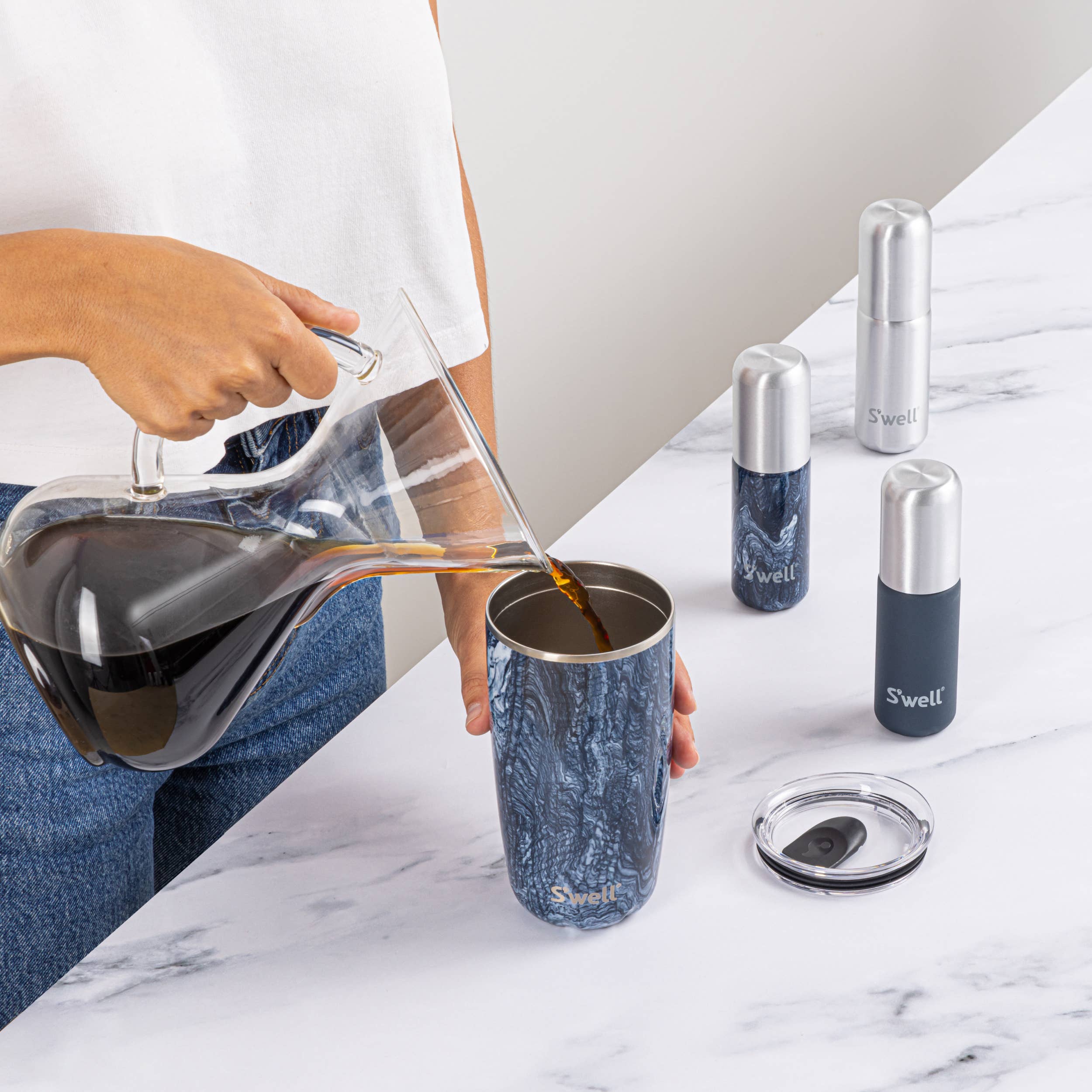 Person pouring coffee into a blue marbled tumbler with S'well branding on a marble surface.
