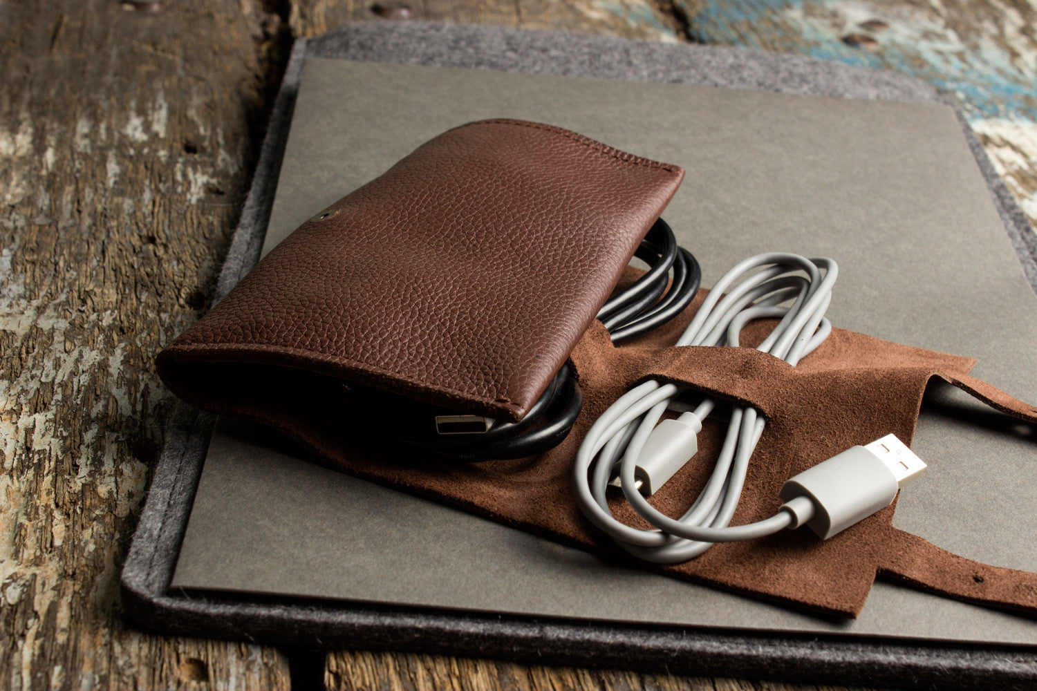 Brown leather wallet with USB cable on a textured surface