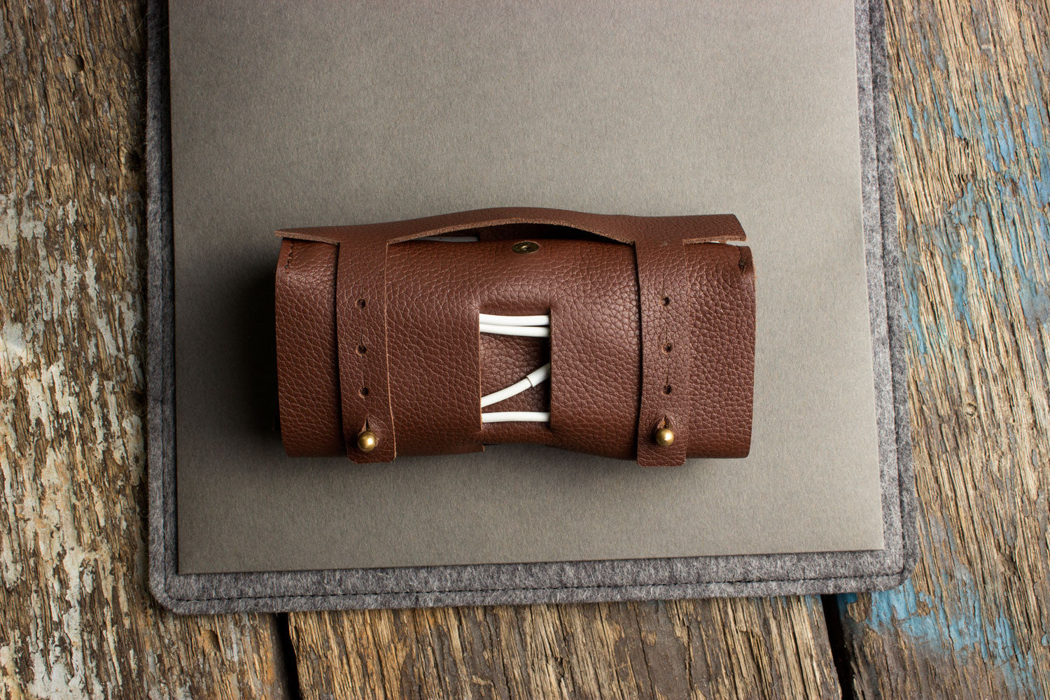 Brown leather roll with white string on a gray surface, placed on a wooden background