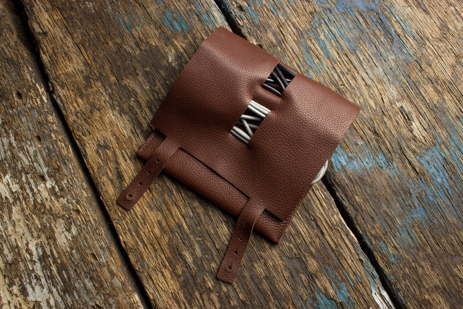 Brown leather pouch with a silver clasp on a wooden surface