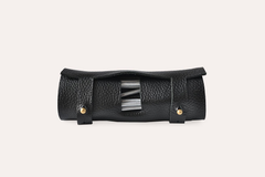 Black leather tool roll with metallic accents on a light beige background