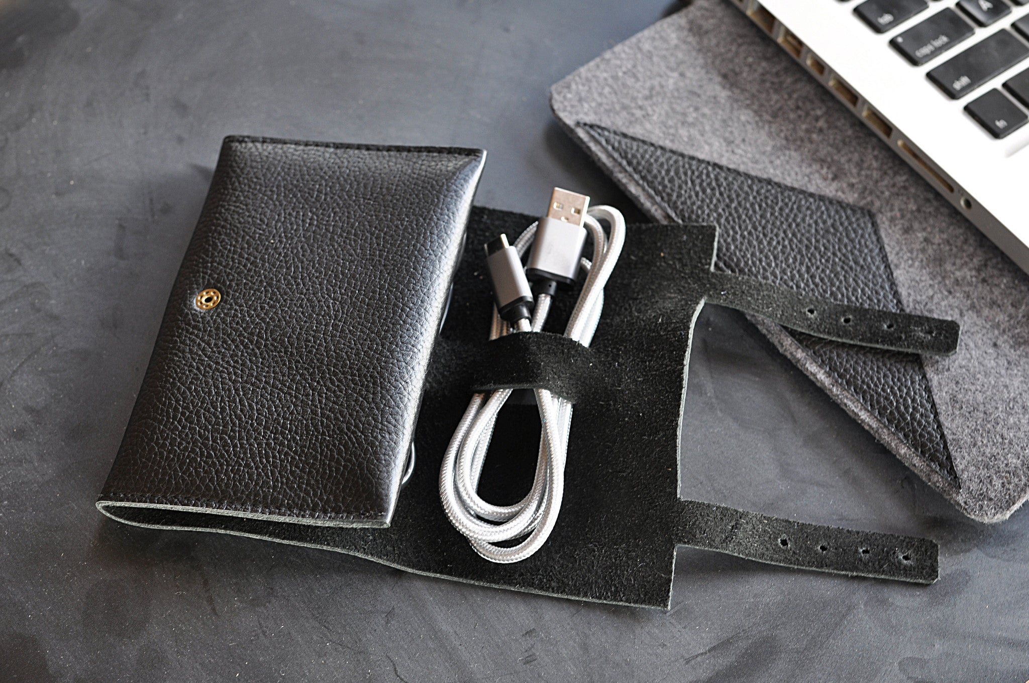 Black leather wallet with USB cable on a gray surface