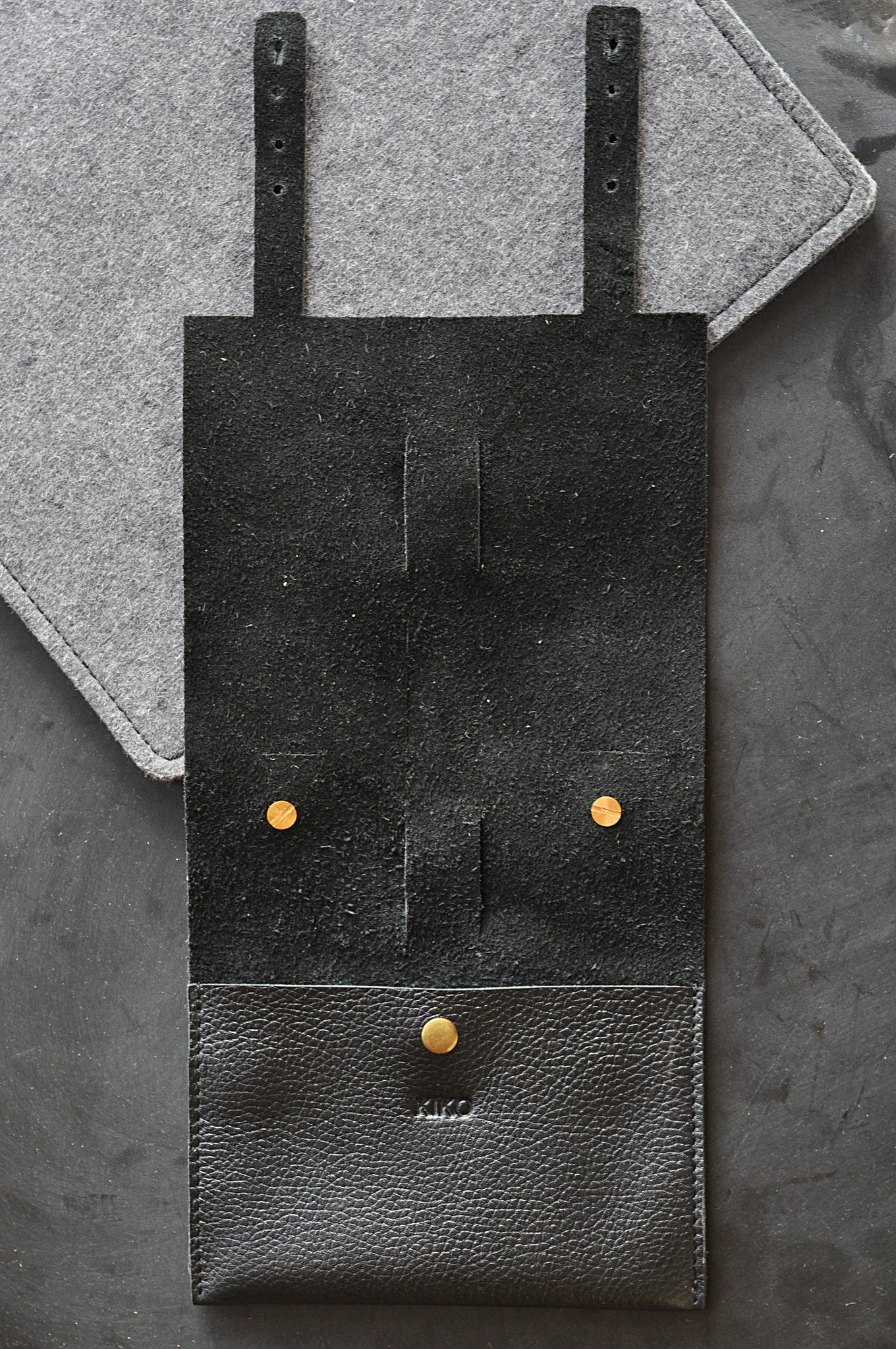 Black leather pouch with gold buttons on a gray textured background