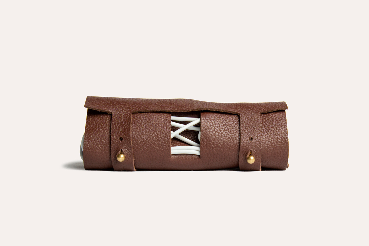 Brown leather roll with white laces on a beige background