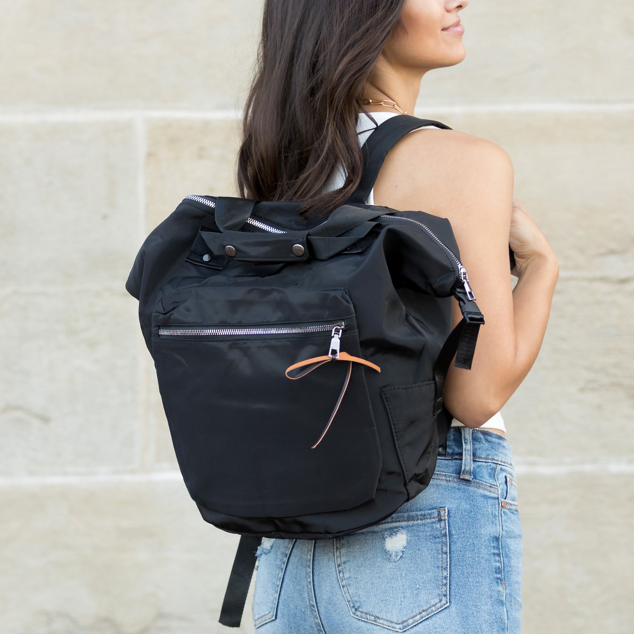 Person wearing a black backpack against a stone wall background
