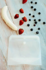 Fruit including strawberries, a banana, and blueberries on a marble surface.