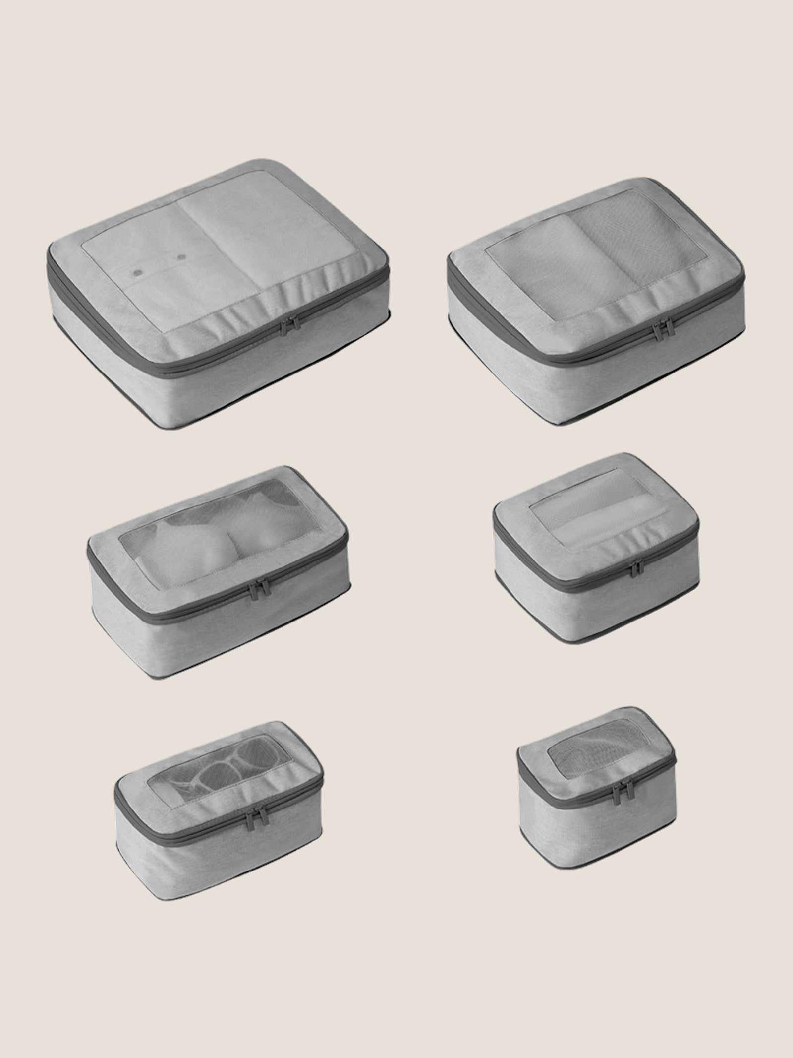 Set of six gray travel packing cubes on a beige background