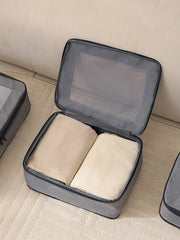 Gray packing cube with beige items on a beige surface