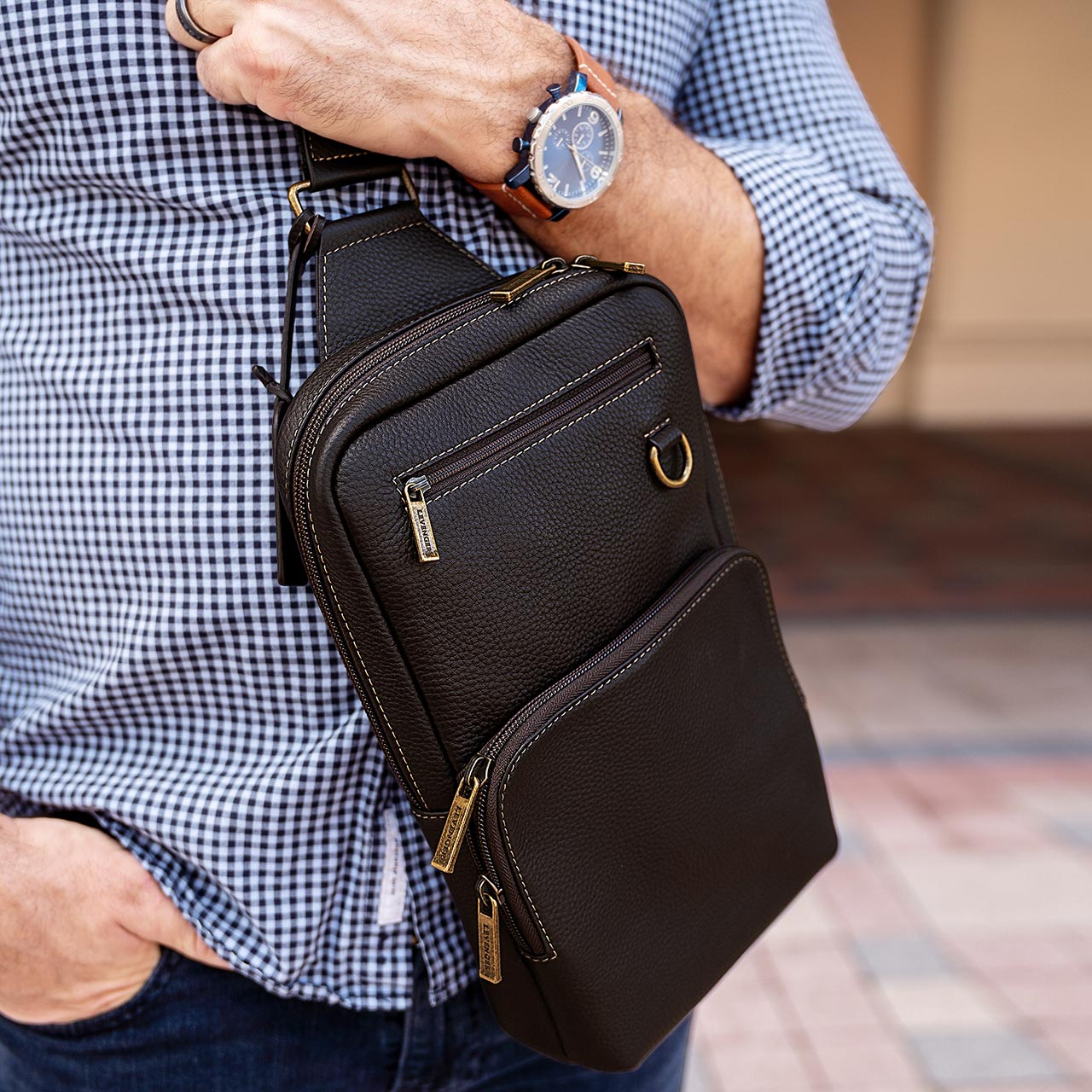 Person holding a black leather crossbody bag with a blurred background