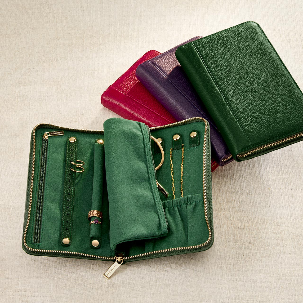 Set of green leather wallets with gold zippers on a beige background