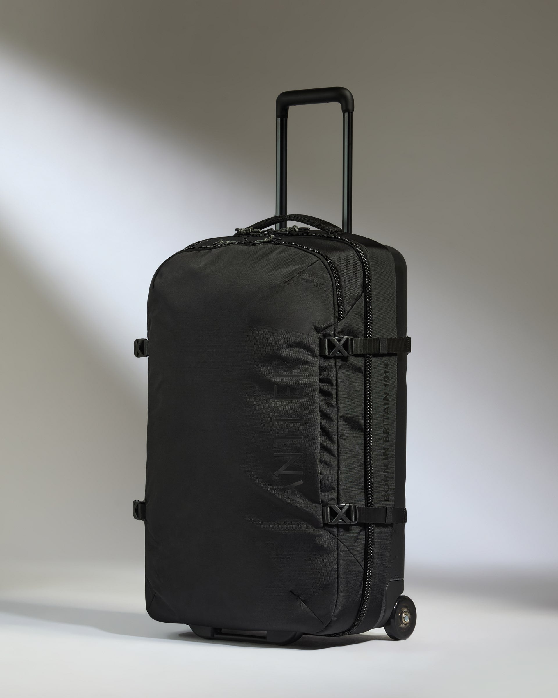 Black suitcase with wheels on a light gray background