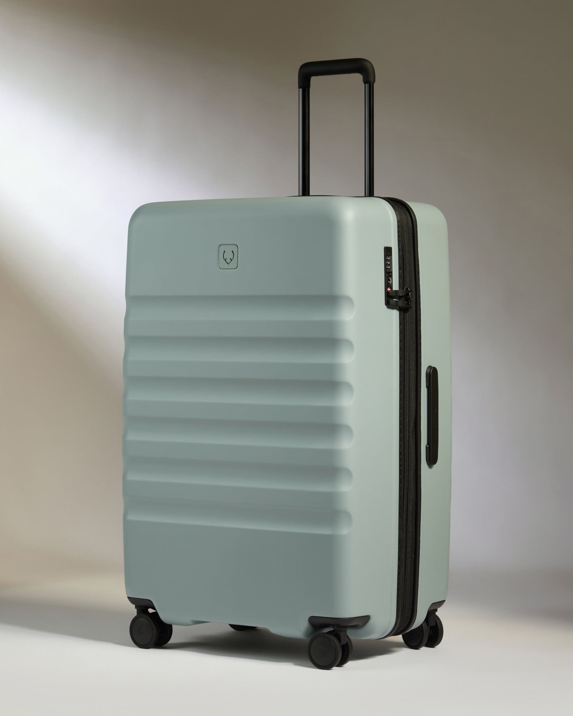Light blue suitcase with black handle and wheels on a neutral background